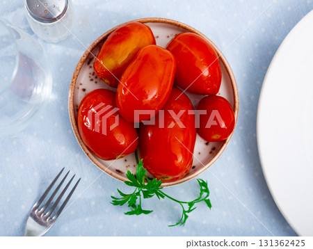 Canned tomatoes on white plate on wooden table 131362425