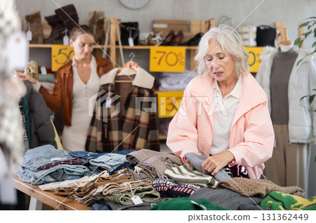 Elderly woman choosing sweaters against the background of female buyer Elderly woman choosing sweaters against the background of female buyer 131362449