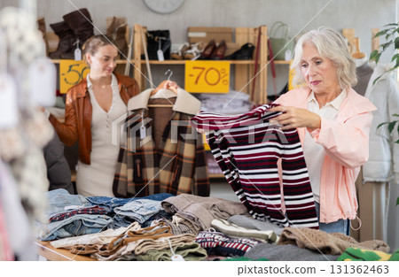 Elderly woman choosing down sweater in clothing store Elderly woman choosing down sweater in clothing store 131362463