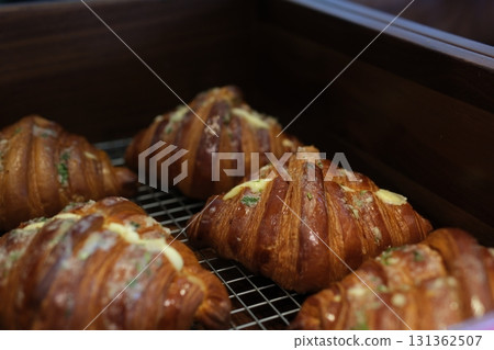 Freshly baked croissants on tray. Fresh food from bakery kitchen. French baked buttery flaky croissant. Breakfast cafe food. Close up of freshly baked croissants on display in a tray for sale in shop  131362507