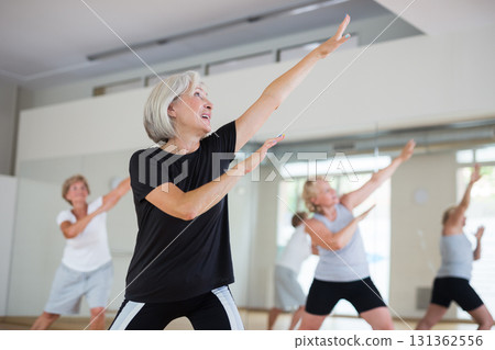 Smiling mature woman enjoying active dancing in dance studio 131362556