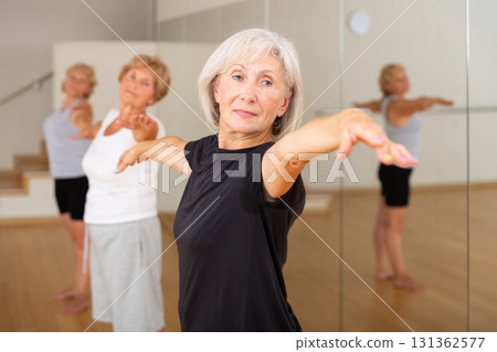 Active mature woman performing stretching during group training Active mature woman performing stretching during group training 131362577