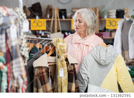 During November sales, mature woman choose and buy coat 131362591