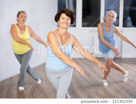 Happy mature woman practicing dance positions during workout session 131362595