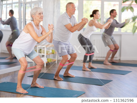 Group of women and men are doing stretching exercise with resistance bands. Good mood and healthy lifestyle concept Group of women and men are doing stretching exercise with resistance bands. Good mood and healthy lifestyle concept 131362596