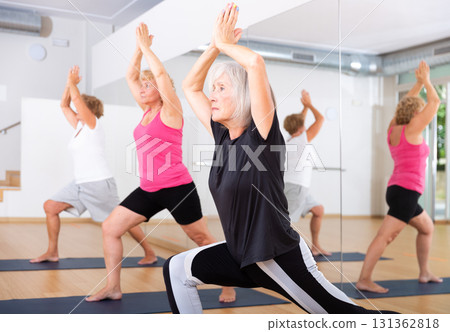 Aged woman performing Anjaneyasana during group yoga training 131362818