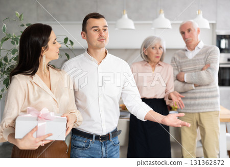 Smiling young couple leaving the house while discontented senior parents standing behind 131362872