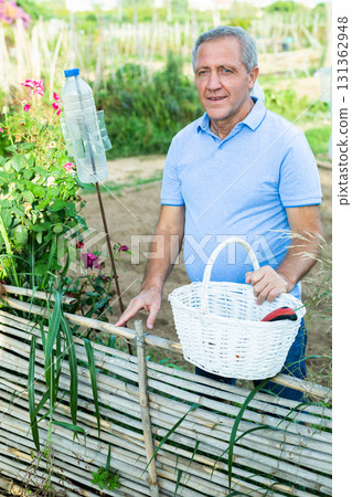 Portrait of positive man at fence in garden Portrait of positive man at fence in garden 131362948