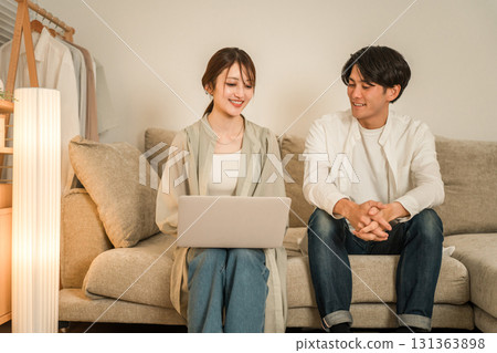 A young Asian couple sitting on the sofa in the living room and looking at a laptop 131363898