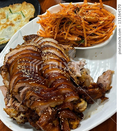Jokbal, a Korean dish of braised pork hock, slow cooked in a rich, savory sauce with soy, garlic, and spices. Tender and flavorful, its often served with lettuce wraps, garlic, and ssamjang Jokbal, a Korean dish of braised pork hock, slow cooked in a rich, savory sauce with soy, garlic, and spices. Tender and flavorful, its often served with lettuce wraps, garlic, and ssamjang 131364570