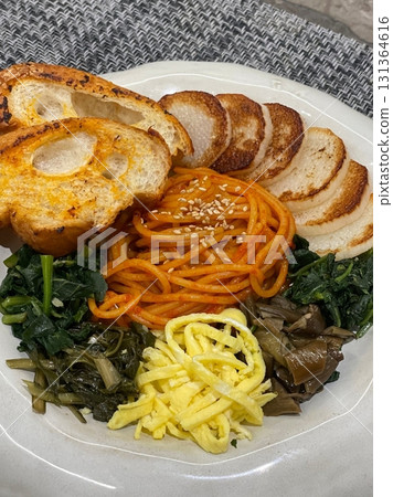 Bibimyeon, a flavorful Korean dish featuring cold noodles tossed in a spicy, tangy sauce, topped with fresh vegetables and a boiled egg. Perfect for summer meals, showcasing vibrant flavors and colors 131364616