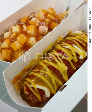 Korean corn dog, a crispy snack coated in a sweet batter, often stuffed with sausage, cheese, or both. Topped with sugar, ketchup, or mustard for a delightful mix of flavors and textures. Korean corn dog, a crispy snack coated in a sweet batter, often stuffed with sausage, cheese, or both. Topped with sugar, ketchup, or mustard for a delightful mix of flavors and textures. 131364620