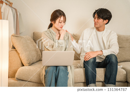 丈夫焦急地看著坐在客廳沙發上用電腦工作的妻子(加班、把工作帶回家、隱性加班) 丈夫焦急地看著坐在客廳沙發上用電腦工作的妻子(加班、把工作帶回家、隱性加班) 131364787