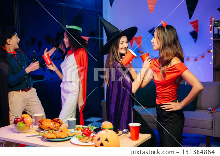 Joyful office Halloween party with coworkers in costumes, celebrating with drinks and laughter, fostering teamwork Joyful office Halloween party with coworkers in costumes, celebrating with drinks and laughter, fostering teamwork 131364864