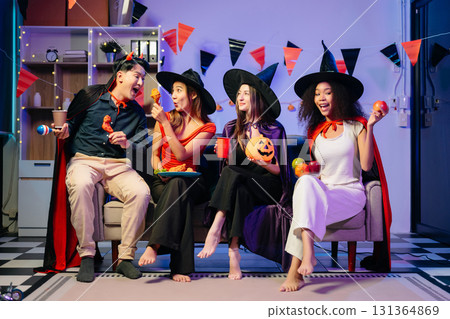 Joyful office Halloween party with coworkers in costumes, celebrating with drinks and laughter, fostering teamwork 131364869