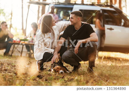 Beautiful couple is sitting with their dog. Group of friends are having fun together in the forest Beautiful couple is sitting with their dog. Group of friends are having fun together in the forest 131364890