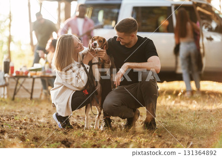 Beautiful couple is sitting with their dog. Group of friends are having fun together in the forest 131364892
