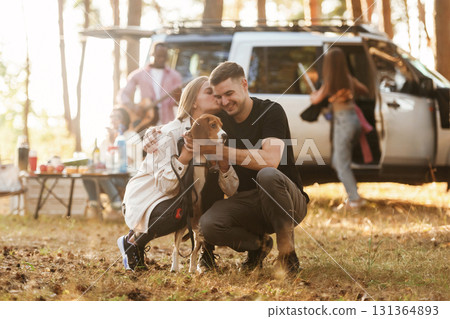 Beautiful couple is sitting with their dog. Group of friends are having fun together in the forest 131364893