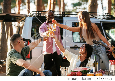 Making cheers with beer bottles. Group of friends are having fun together in the forest Making cheers with beer bottles. Group of friends are having fun together in the forest 131364894