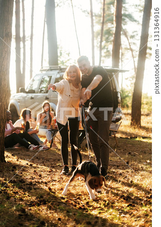 Cute couple is with their beagle dog. Group of friends are having fun together in the forest Cute couple is with their beagle dog. Group of friends are having fun together in the forest 131364916