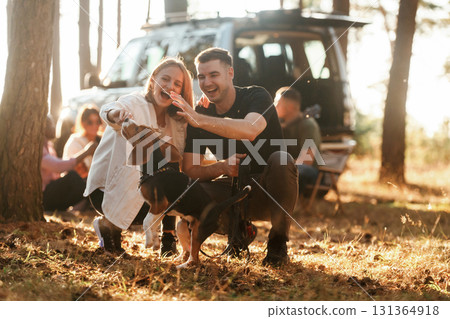Cute couple is with their beagle dog. Group of friends are having fun together in the forest 131364918