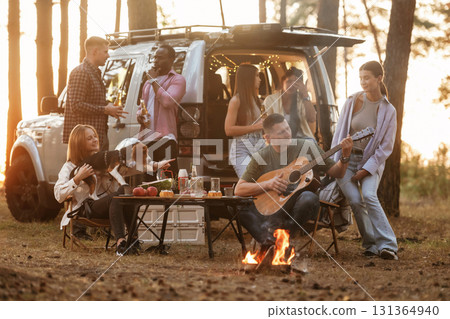 By the campfire. Group of friends are having fun together in the forest By the campfire. Group of friends are having fun together in the forest 131364940