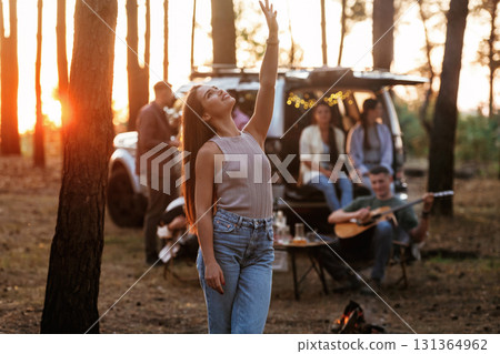 Pretty woman is standing and enjoying nature. Group of friends are having fun together in the forest Pretty woman is standing and enjoying nature. Group of friends are having fun together in the forest 131364962