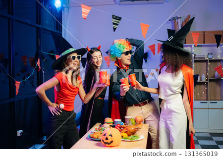 Joyful office Halloween party with coworkers in costumes, celebrating with drinks and laughter, fostering teamwork 131365019