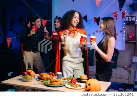 Joyful friends in vibrant Halloween costumes share drinks and laughter at a festive indoor party. Joyful friends in vibrant Halloween costumes share drinks and laughter at a festive indoor party. 131365241