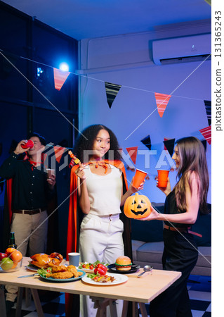 Joyful friends in vibrant Halloween costumes share drinks and laughter at a festive indoor party. Joyful friends in vibrant Halloween costumes share drinks and laughter at a festive indoor party. 131365243