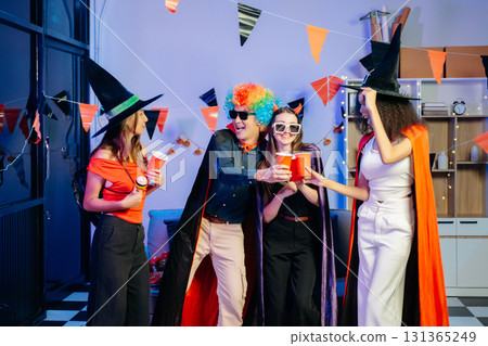 Joyful office Halloween party with coworkers in costumes, celebrating 131365249