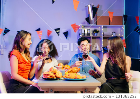 Friends celebrate indoors with food and wine, sharing laughs and toasts at a festive gathering. Friends celebrate indoors with food and wine, sharing laughs and toasts at a festive gathering. 131365252