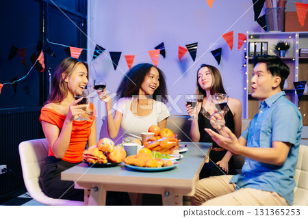 Friends celebrate indoors with food and wine, sharing laughs and toasts at a festive gathering. Friends celebrate indoors with food and wine, sharing laughs and toasts at a festive gathering. 131365253