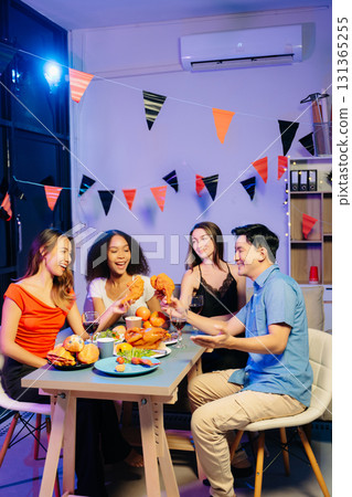 Friends celebrate indoors with food and wine, sharing laughs and toasts at a festive gathering. Friends celebrate indoors with food and wine, sharing laughs and toasts at a festive gathering. 131365255