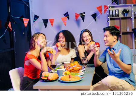 Friends celebrate indoors with food and wine, sharing laughs and toasts at a festive gathering. Friends celebrate indoors with food and wine, sharing laughs and toasts at a festive gathering. 131365256