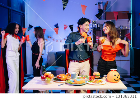 Joyful friends in vibrant Halloween costumes share drinks and laughter at a festive indoor party. Joyful friends in vibrant Halloween costumes share drinks and laughter at a festive indoor party. 131365311
