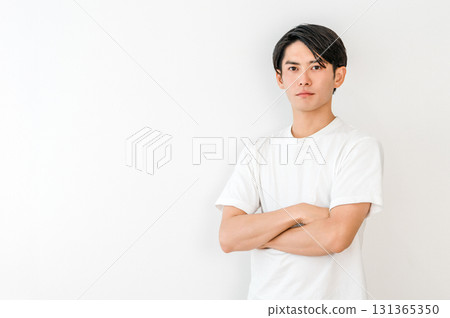 Smiling Asian man in a t-shirt with his arms crossed Smiling Asian man in a t-shirt with his arms crossed 131365350