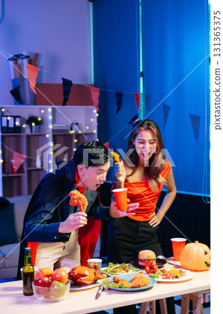 Joyful friends in vibrant Halloween costumes share drinks and laughter at a festive indoor party. Joyful friends in vibrant Halloween costumes share drinks and laughter at a festive indoor party. 131365375