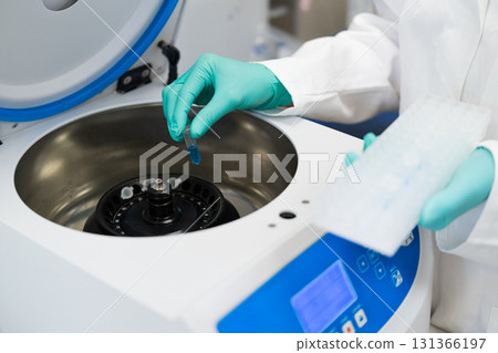 Woman hands in rubber gloves insert test tubes to centrifuge in chemical laboratory Woman hands in rubber gloves insert test tubes to centrifuge in chemical laboratory 131366197