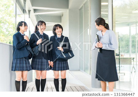 Friendly female students walking through the school building with smiles saying hello to the teacher (going to school, going home, commuting to school) 131366447
