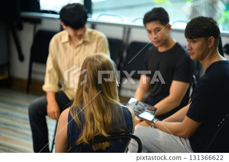 Diverse group of people sitting in a circle engaging in open conversation during a therapy session Diverse group of people sitting in a circle engaging in open conversation during a therapy session 131366622