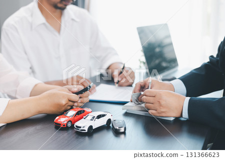 Customer paying cash to dealer with car loan contract, vehicle models on desk, concept of auto purchase, finance, leasing, insurance, successful transaction and business agreement. car loan contract Customer paying cash to dealer with car loan contract, vehicle models on desk, concept of auto purchase, finance, leasing, insurance, successful transaction and business agreement. car loan contract 131366623