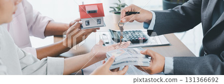 Panorama of real estate deal with house models, key handover, cash money, and calculator on desk, symbolizing property investment, mortgage loan, housing purchase, and financial planning success. Panorama of real estate deal with house models, key handover, cash money, and calculator on desk, symbolizing property investment, mortgage loan, housing purchase, and financial planning success. 131366692