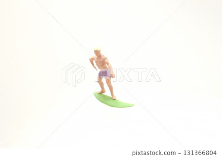 Miniature Surfer Figure On Green Surfboard Over Clear Surface Miniature Surfer Figure On Green Surfboard Over Clear Surface 131366804