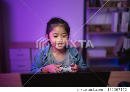 Young girl playing video games at home, enjoying time in cozy gaming setup with colorful lighting, wearing casual attire, focused and happy expression 131367152