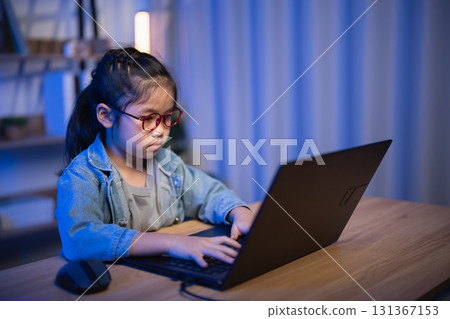 Focused Young Girl Using Laptop in Cozy Evening Environment with Natural Light and Warm Tones 131367153