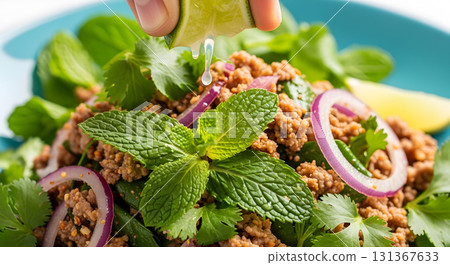Larb salad closeup with lime being squeezed on top. Larb salad closeup with lime being squeezed on top. 131367633