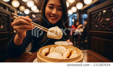 Asian woman enjoying delicious soup dumplings with chopsticks in restaurant Asian woman enjoying delicious soup dumplings with chopsticks in restaurant 131367634