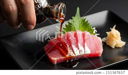 Pouring soy sauce on fresh tuna sashimi with garnish. Pouring soy sauce on fresh tuna sashimi with garnish. 131367637