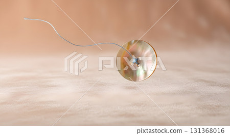 Mother of pearl button with thread on beige textured background. 131368016